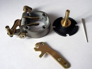 Dosierabteilung: Gehäuse zur Aufnahme der Kraftstoffdüse. Über die Einstellschraube wird das korrekte Leerlaufgemisch eingestellt, das Hebelwerk steuert die Kaltstartanreicherung.